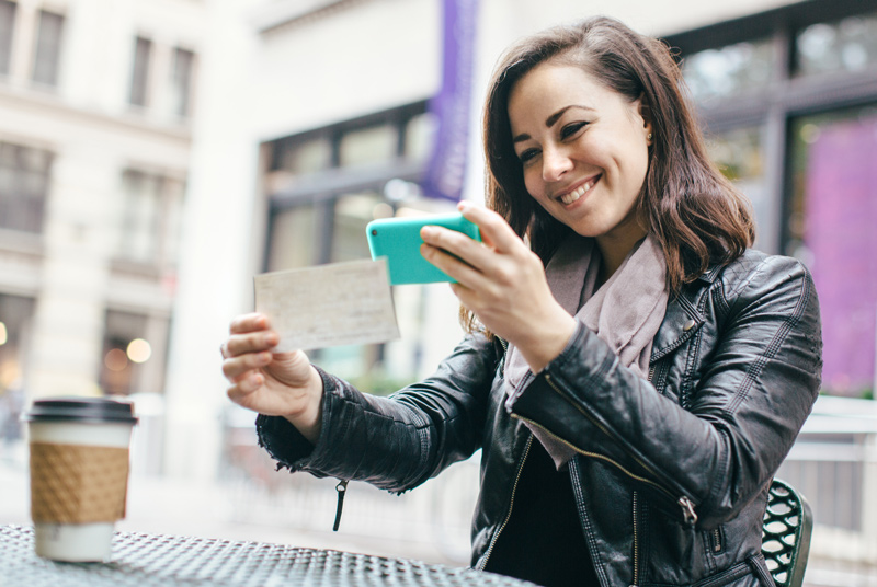 Woman smiling making a mobile check deposit.
