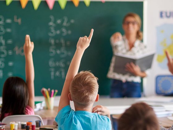 Children at school raising their hands to answer the teacher.