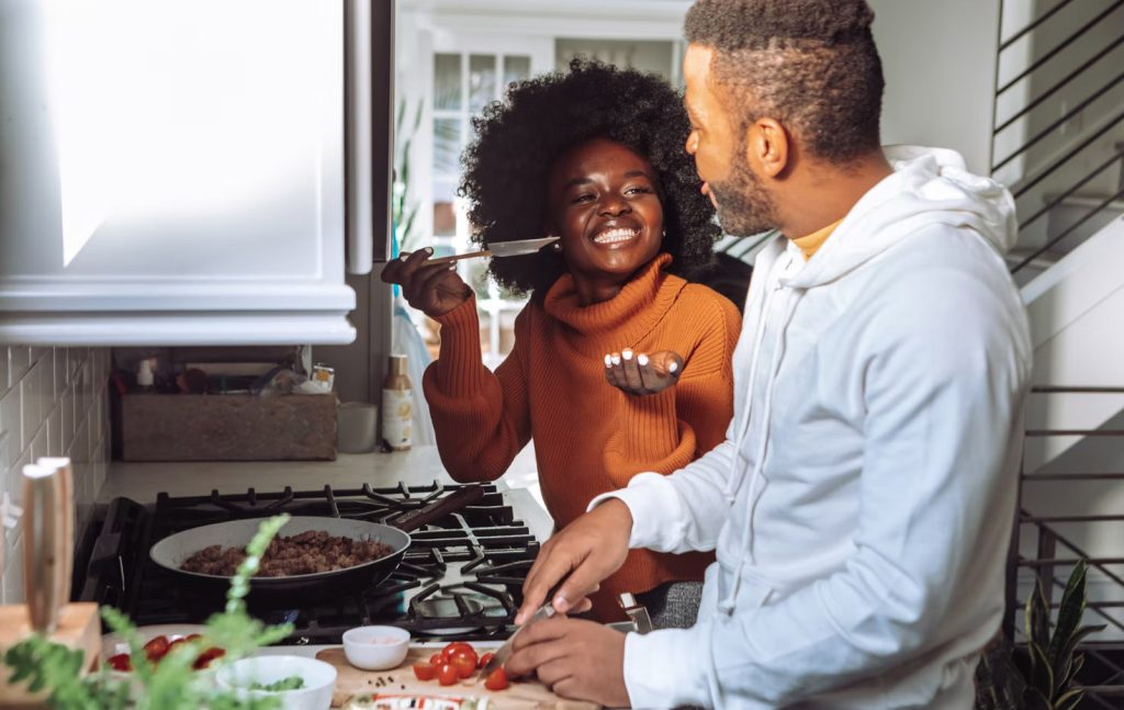 A young couple cooking dinner ties back to the theme that a key ingredient to your financial success is establishing and maintaining good credit habits.